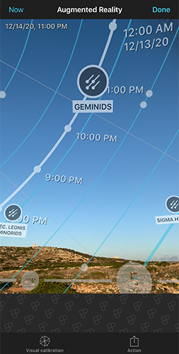 Augmented reality view showing the Geminids meteor shower radiant path overlaid on a real evening landscape, with time markers